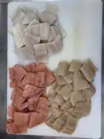 Drei Sorten Forellenmatjesstuecke auf einem Schneidbrett
