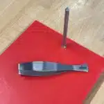 Graetenpinzette aus Edelstahl auf rotem Schneidbrett