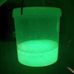 Ein Becher Libra Lures Silikonmasse in Glow mit UV Licht angeleuchtet