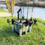 UL Rodstand mit Angelruten auf Wiese vor einem Gewaesser